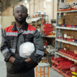 young-serious-african-american-male-engineer-workwear-holding-hardhat